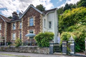 una vecchia casa di mattoni con una recinzione in pietra di The Coach House a Malvern Wells