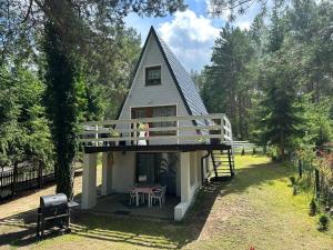 a small house with a gambrel roof and a deck at Domek w zaciszu in Grzybowo
