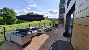 a patio with couches and an umbrella on a deck at P R A T U M Plus in Mikołajki