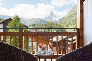 due bicchieri di vino su un balcone con montagne di Europe Hotel & Spa a Zermatt