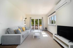 a living room with a couch and a flat screen tv at WHome Modern House With Balcony & AC Close To The Sea in Alcabideche