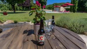two bottles of beer on a wooden table with a plant at Ancienne grange rénovée avec piscine in Vaillac +15 photos