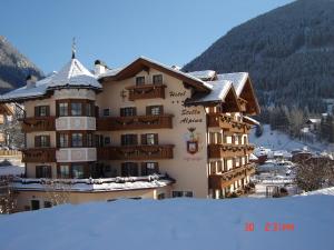 un edificio con la neve sul terreno di fronte ad esso di Hotel Stella Alpina a Moena