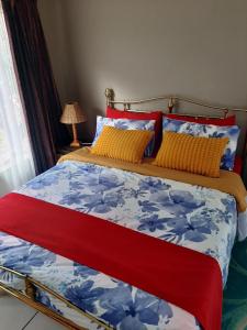 a bedroom with a bed with blue and yellow pillows at Villa at Wekker in Pretoria