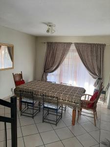 a dining room with a table and chairs and a window at Villa at Wekker in Pretoria