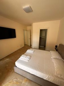 a bedroom with a large white bed and a flat screen tv at Casa Florean in Cicciano