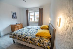 una camera da letto con un letto con lenzuola gialle e una finestra di Gîte A l'ombre du clocher a Mackenheim
