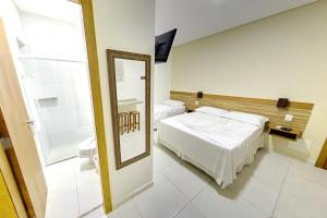 ein Hotelzimmer mit einem Bett und einem Spiegel in der Unterkunft Pousada Canto da Praça in Bertioga