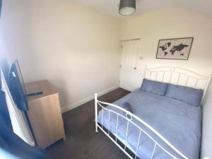 a small bedroom with a blue bed and a tv at 4-5 Bedroom House For Corporate Stays in Kettering in Kettering
