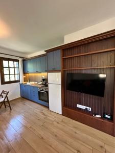 a kitchen with blue cabinets and a large television at Elgi Cottage in Chrysi Ammoudia