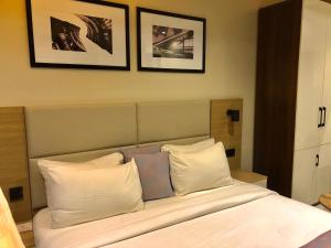 a bed with white pillows and two pictures on the wall at Ringruby Hotel, Oduduwa Way in Ikeja