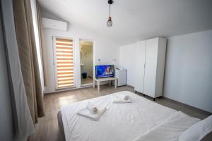 a bedroom with a white bed and a television at Casa Amalia in Costinesti