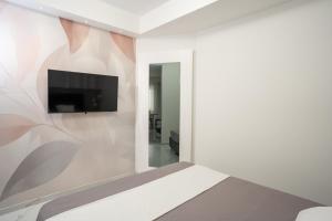 a bedroom with a flat screen tv on a wall at Th Luxury Apartment Taormina in Taormina