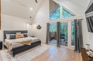 een slaapkamer met een bed en een groot raam bij The Echo - Forest Romance with Sunken Hot Tub Underneath the Starlit Night in Broken Bow