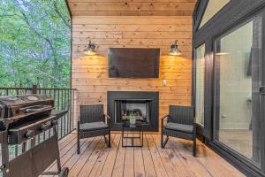 een afgeschermde veranda met een open haard en een flatscreen-tv bij The Echo - Forest Romance with Sunken Hot Tub Underneath the Starlit Night in Broken Bow