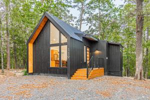 een zwart tiny house in the woods bij The Echo - Forest Romance with Sunken Hot Tub Underneath the Starlit Night in Broken Bow
