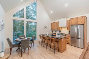 een keuken met een tafel, stoelen en een koelkast bij The Echo - Forest Romance with Sunken Hot Tub Underneath the Starlit Night in Broken Bow