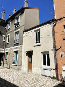 an old building with a brown door on a street at Charming Cozy Cottage Palaiseau Center in Palaiseau