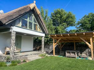 a cottage with a thatched roof and a patio at Zanzara Guesthouse in Pákozd