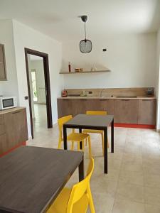 a kitchen and dining room with yellow chairs and tables at B&B Villa Verde in Pesche