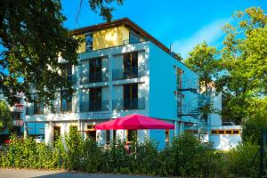 un edificio blu con un ombrello rosa davanti di Hotel Ambassador-Berlin Grünau a Berlino