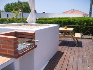 a barbecue on a deck with a picnic table at Casa Amarela in Zambujeira do Mar
