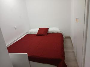 a small bed with a red blanket in a room at Piso onada1 in Empuriabrava