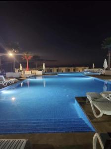 a large swimming pool at night with chairs at Prestigia plage des nations in Sale