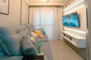 a living room with a couch and a flat screen tv at Apartamento Sofisticado Perto de Tudo JR1304 in Maringá