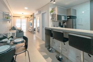 a kitchen and living room with a table and chairs at Apartamento Sofisticado Perto de Tudo JR1304 in Maringá