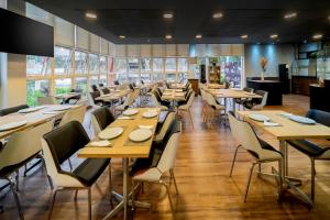 a restaurant with wooden tables and chairs and windows at ibis budget Piracicaba in Piracicaba +96 photos