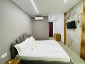 Un dormitorio con una gran cama blanca y un televisor. en Imperial Hotel, en Shënkoll