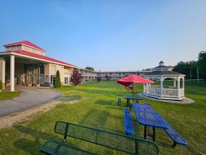 奥本Center Street Value Inn的草地上的两张野餐桌和一把红伞