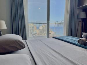 a bedroom with a large bed with a large window at Duplex Penthouse Prime Location in St Julian's