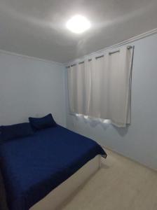 una camera con letto blu e tenda bianca di Apto pé na Areia a Ilha do Frade