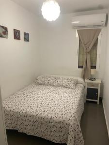a white bedroom with a bed and a window at Apartamento Casa Quiles in Losa del Obispo