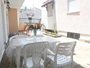 einen weißen Tisch mit weißen Stühlen und eine Vase aus Blumen in der Unterkunft νέα ηρακλειτσα όμορφο διαμέρισμα in Nea Iraklitsa