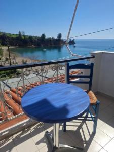 a blue table on a balcony with a view of the ocean at Agnanti Kotsikia in Kotsikiá