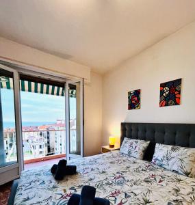 a bedroom with a bed and a large window at Azure Horizons Seaside Escape in Beaulieu-sur-Mer