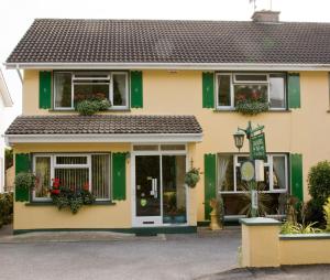 a yellow house with green trim and windows at Danabel B&B in Kinsale