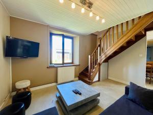 a living room with a couch and a tv at La Maison d Utah Beach and Memory in Sainte-Marie-du-Mont