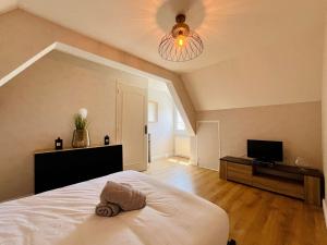 a bedroom with a white bed and a television at La Maison d Utah Beach and Memory in Sainte-Marie-du-Mont