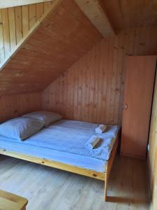 a bed in a wooden room with a attic at Agroturystyka za wodą - apartamenty in Kacwin