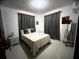 a bedroom with a white bed with black curtains at Family Apartment in San Isidro in Mendoza