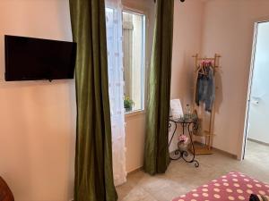 a living room with a television and a window at Maison sol en ciel Petit Dejeuner et Parking inclus in Aigues-Mortes