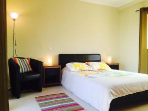 een slaapkamer met een bed en een zwarte stoel bij Albufeira Luxury Villa in Albufeira +51 foto's