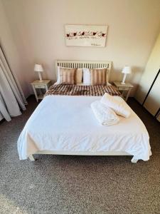 a bedroom with a large white bed with two tables at LaMer No 5 in Stilbaai +12 photos