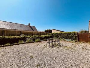 a building with a bench in a gravel yard at La Maison d Utah Beach and Memory in Sainte-Marie-du-Mont