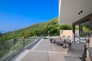 a patio with chairs and a table on a balcony at Villa Marmonte, Luksuzna vila s bazenom i pogledom na more in Medveja