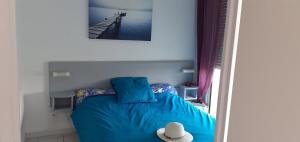 a bedroom with a blue bed with a hat on it at Appartement du Golf de Ciboure in Ciboure